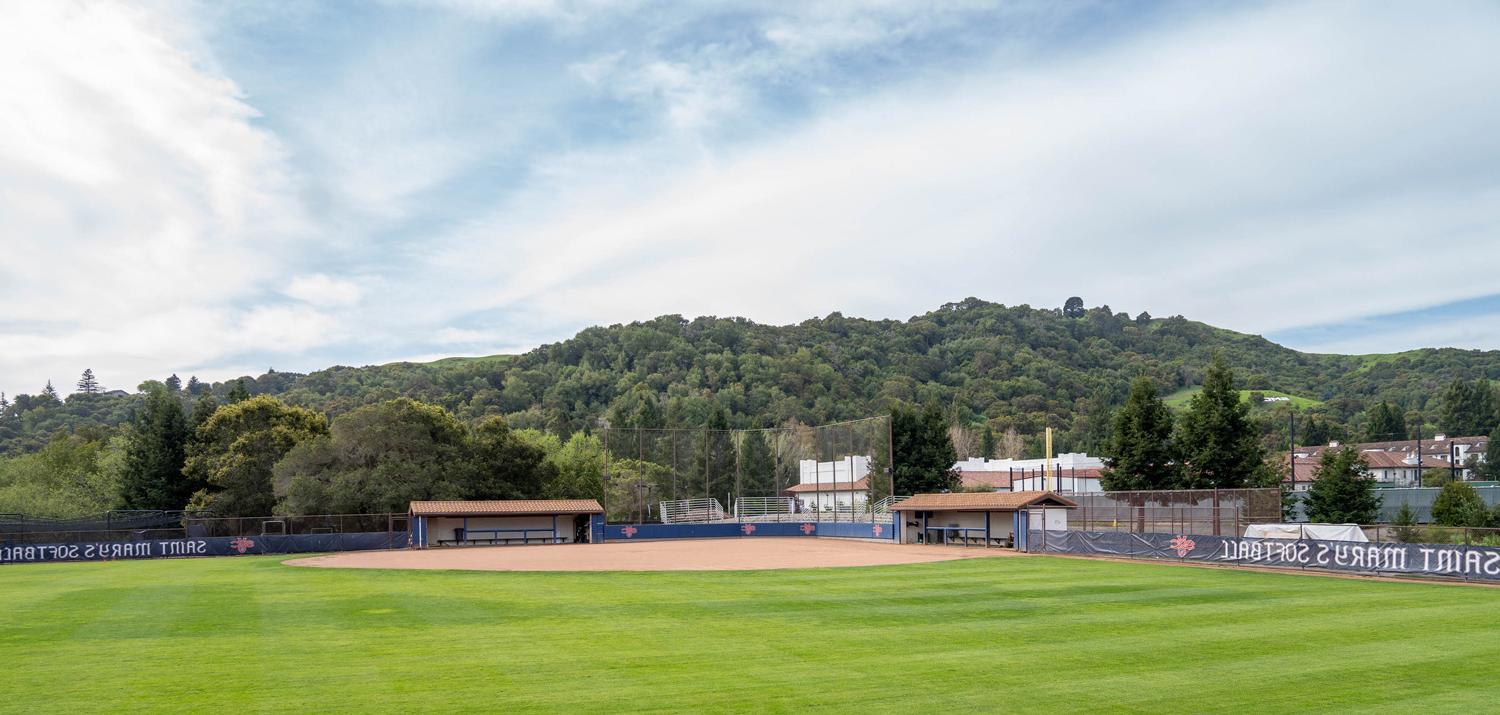 softball field with green grass and hills behind
