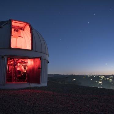 An observatory at the top of a hill at night