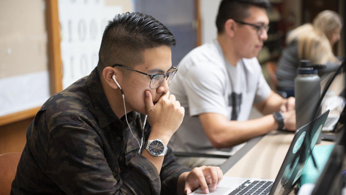 一个学生戴着耳机在电脑上工作 